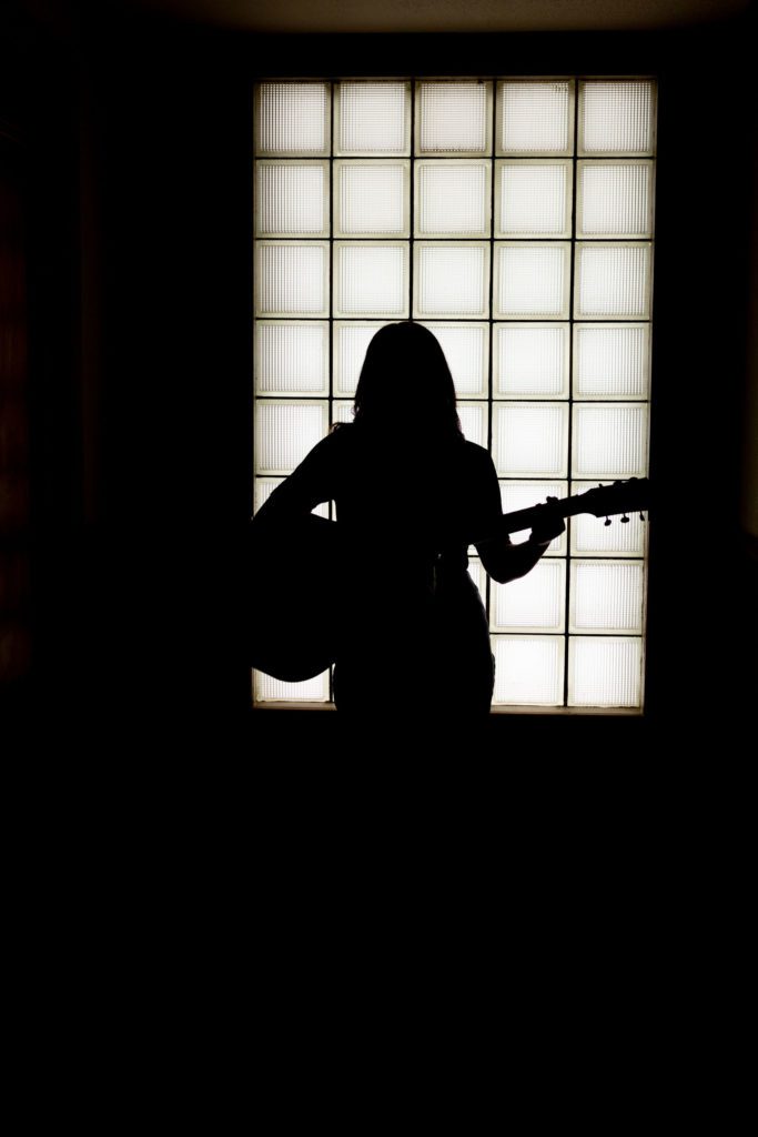 Silhouette portrait of senior girl playing guitar in Mauldin Productions recording studio in Gladewater, TX
