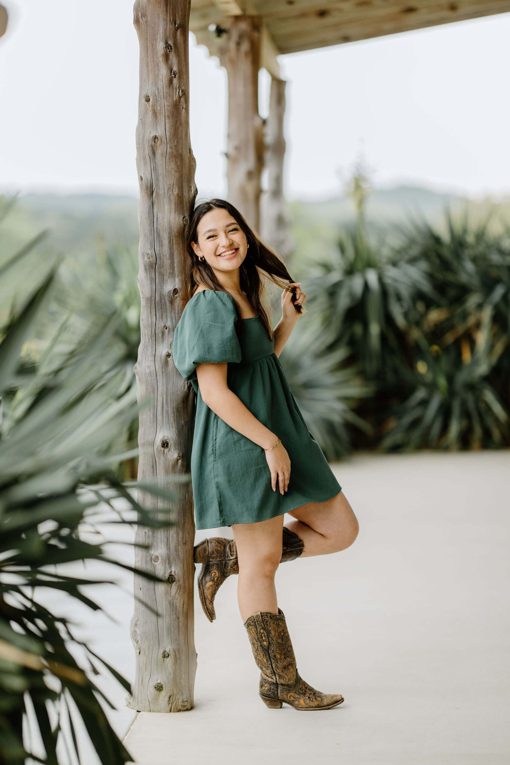Candid portrait of Longview, TX senior girl in green dress and boots at El Cerrito Lodge.