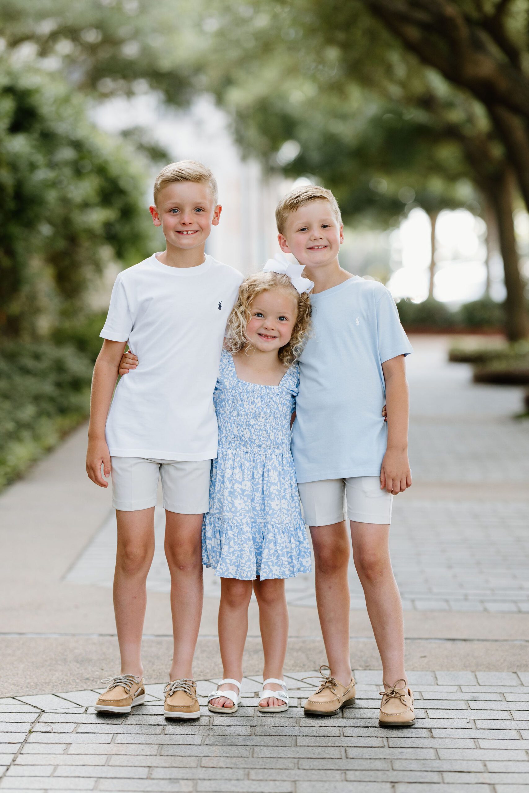 summer family portrait of 3 young siblings in coordinating white and blue outfits