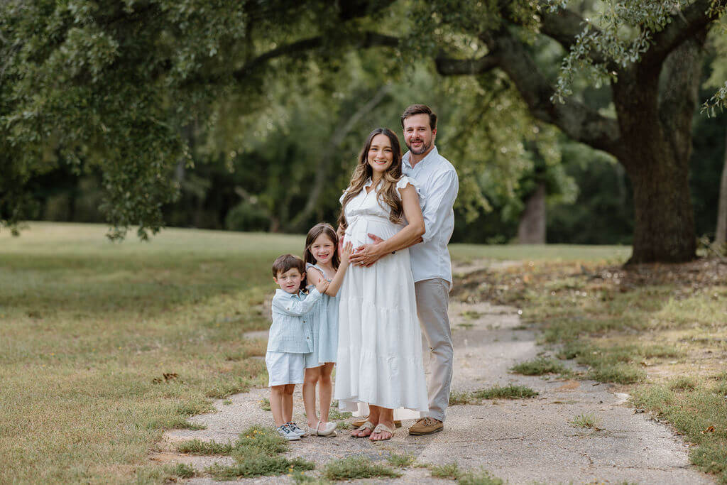 family pictures of young family in neutral colors standing under a large oak tree