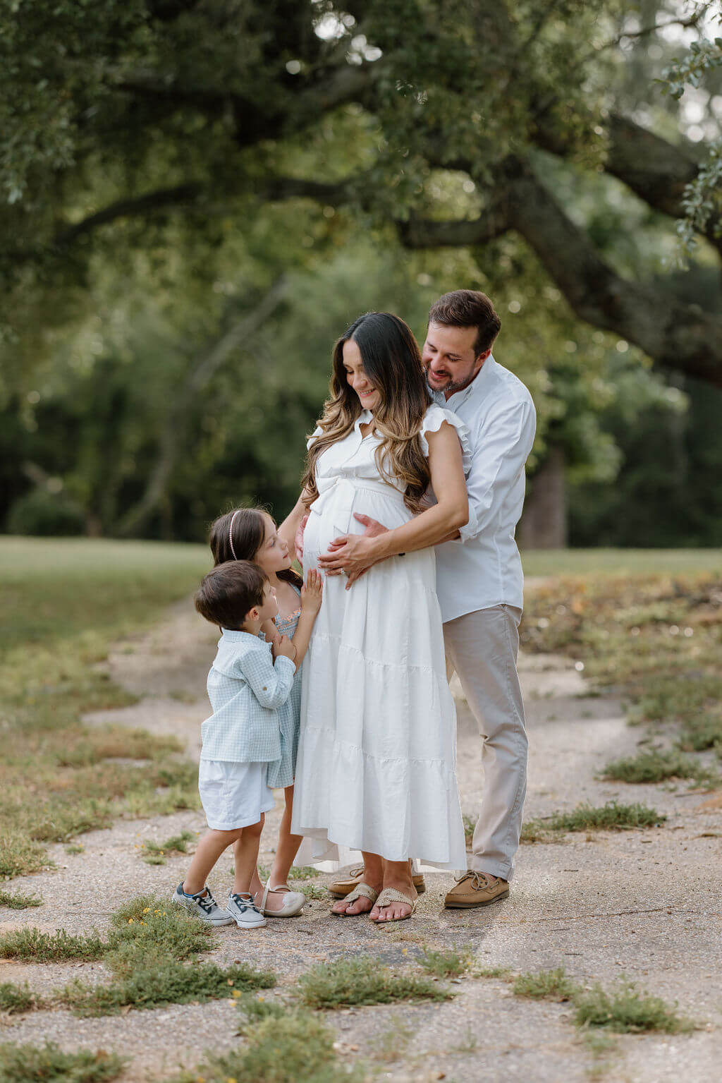 family pictures of young family in neutral colors standing under a large oak tree