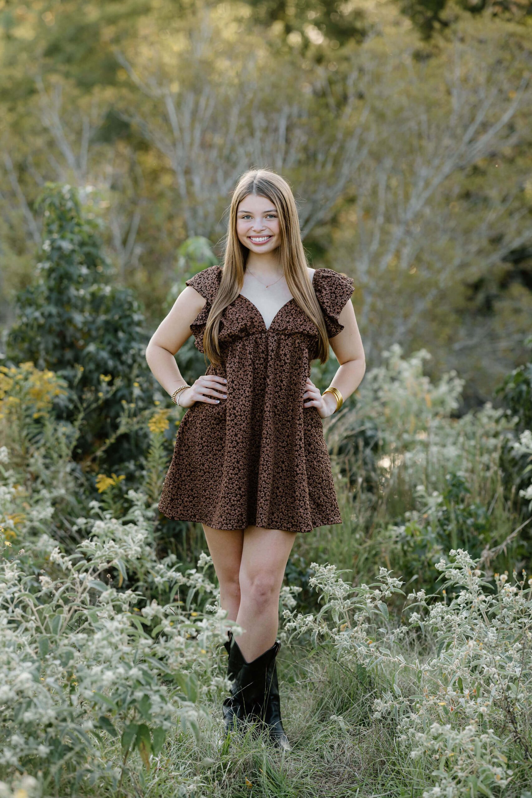 Girl in brown dress standing in field posing for senior pictures in Longview, TX