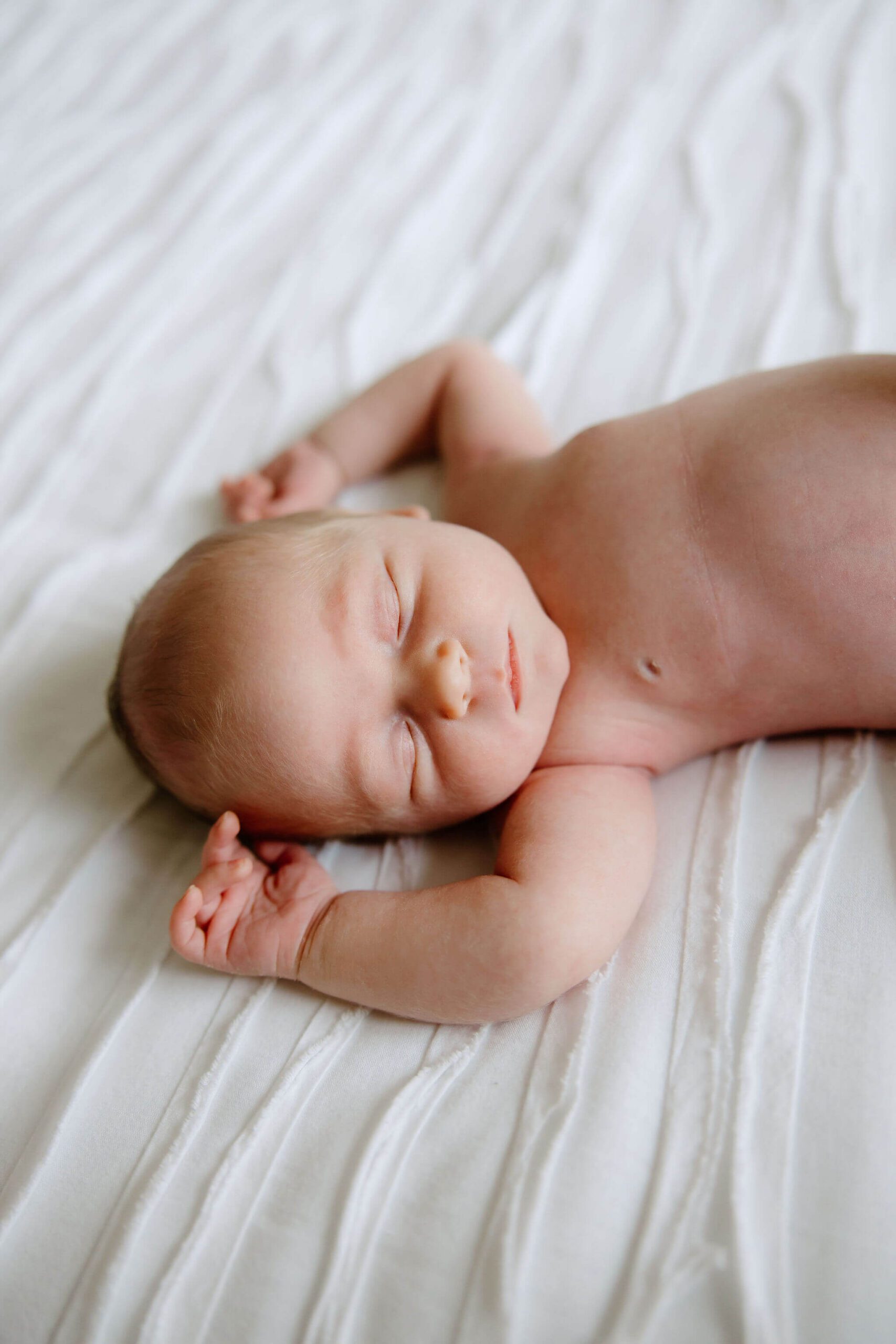 Newborn baby boy lying on a bed during an in-home lifestyle newborn photography session in Longview, Texas